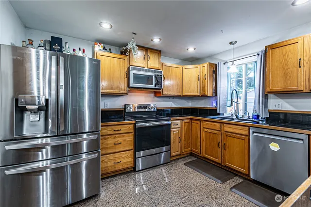 a kitchen with stainless steel appliances granite countertop a sink and a stove