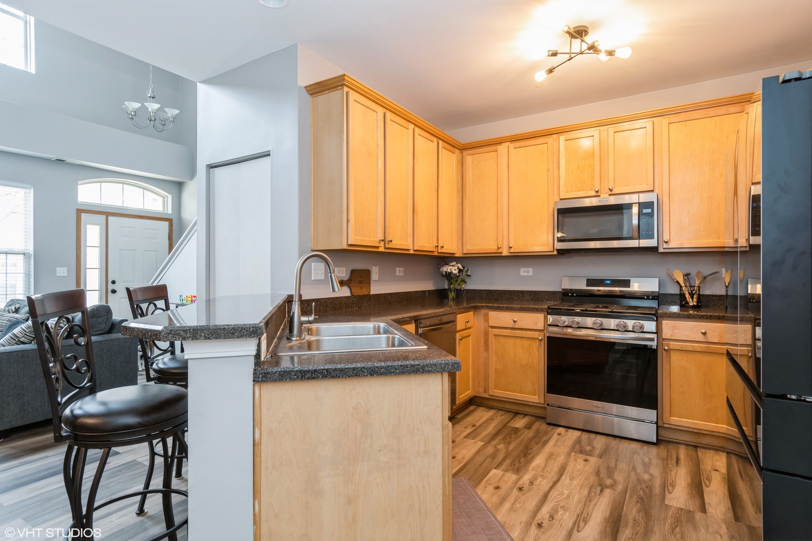 237 Springbrook Trail South, Unit 3 Oswego, IL 60543 - Photo 6 of 17 a kitchen with stainless steel appliances granite countertop a stove top oven a sink dishwasher a dining table and chairs with wooden floor
