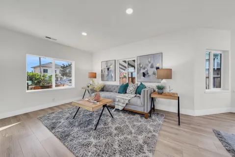 a living room with furniture and kitchen view with wooden floor