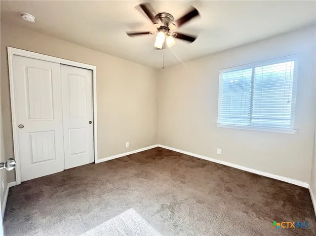 an empty room with windows and fan
