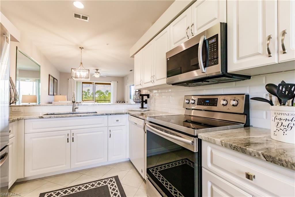3820 Sawgrass Way, Unit 3043 Naples, FL 34112 - Photo 17 of 44 a kitchen with stainless steel appliances granite countertop a stove and a microwave