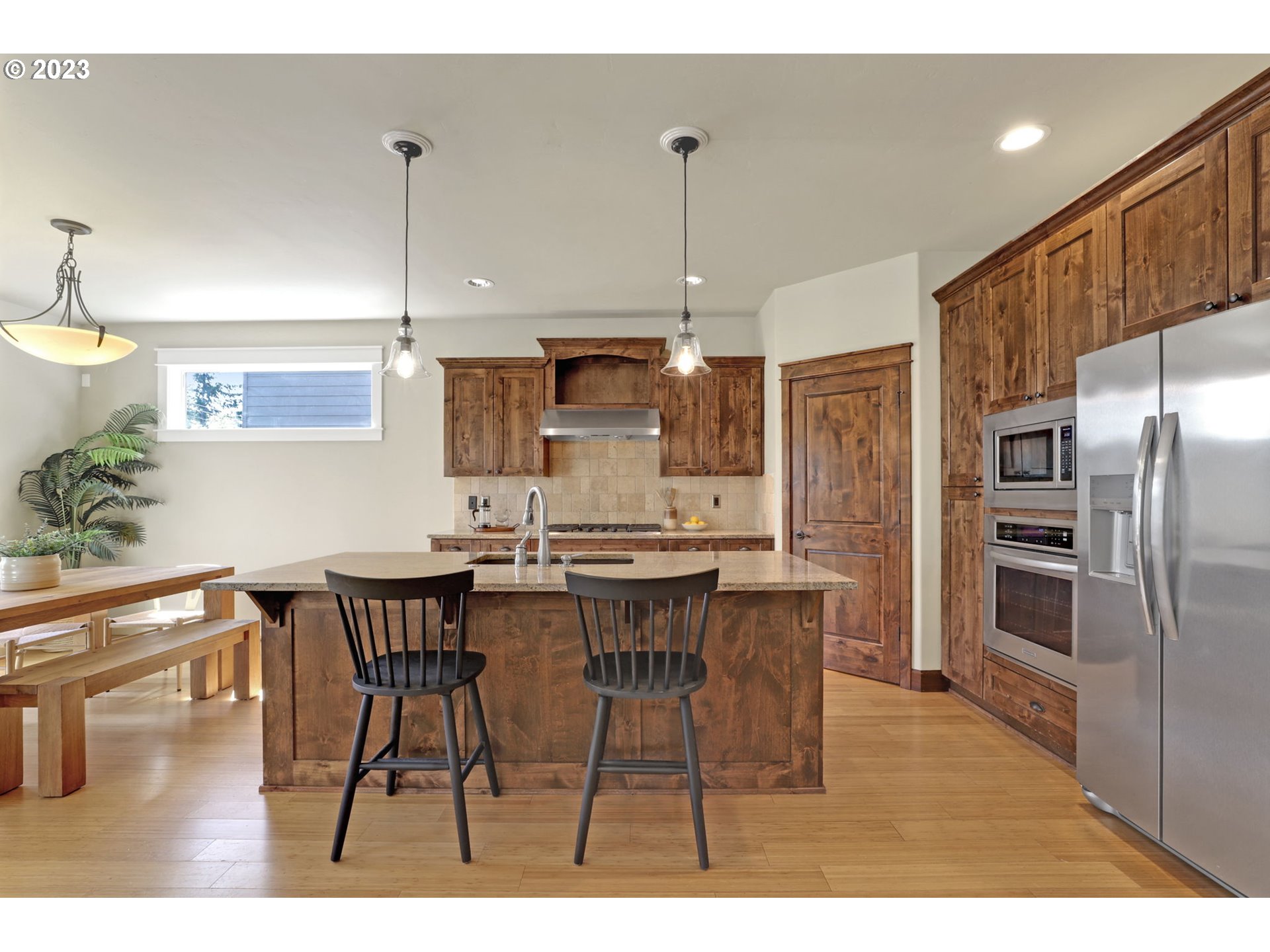 9806 Northwest Wayne Lane Portland, OR 97229 - Photo 7 of 21 a kitchen with stainless steel appliances kitchen island granite countertop a table chairs and a refrigerator