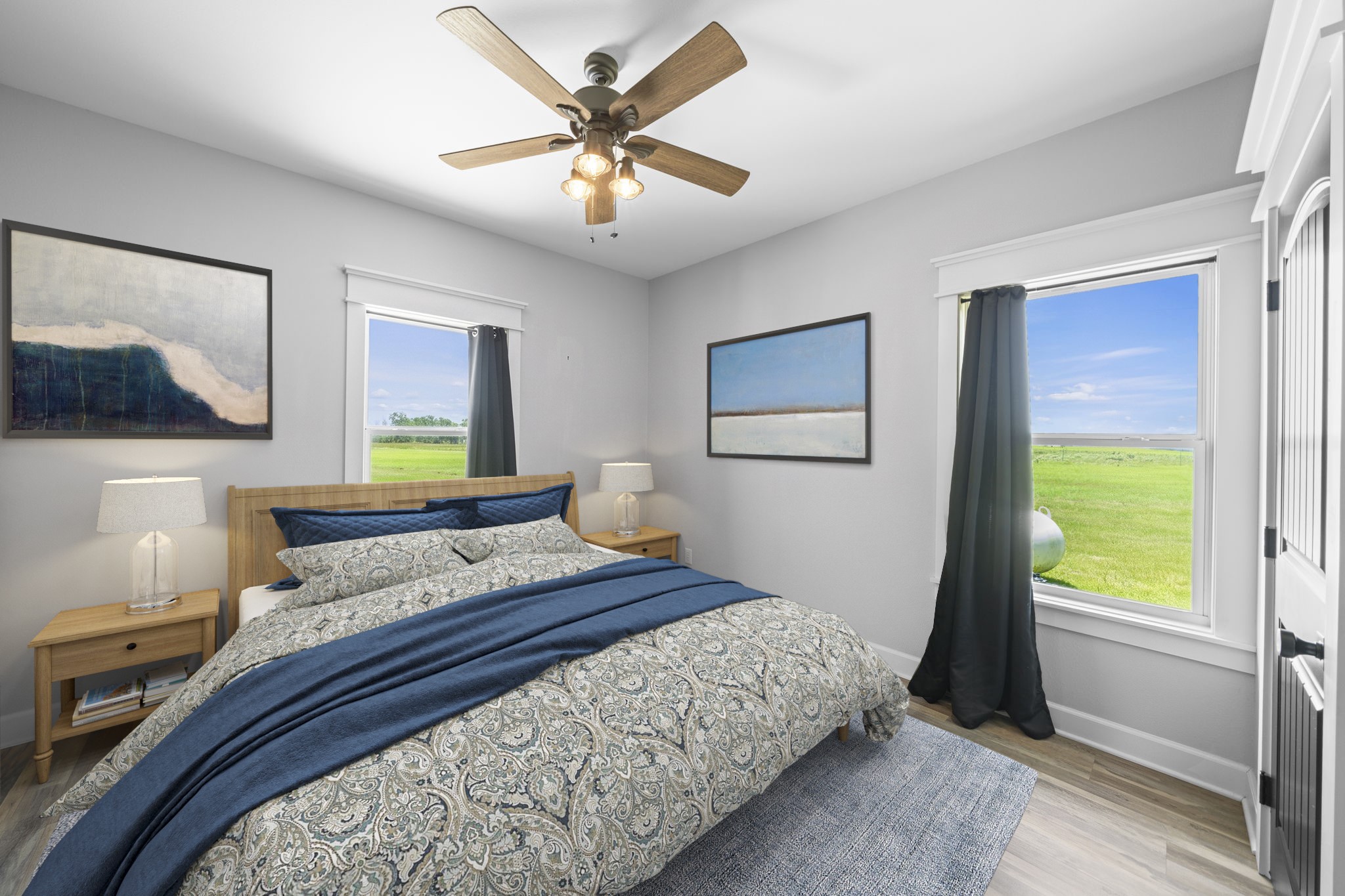 1655 Old Cuero Road Yoakum, TX 77995 - Photo 24 of 24 Virtually Staged: This spacious secondary bedroom offers a bright, inviting layout with durable flooring, neutral paint, and abundant natural light from two large windows overlooking scenic green space. A ceiling fan with an integrated light fixture provides year-round comfort, while the generous floor plan easily accommodates a large bed.
