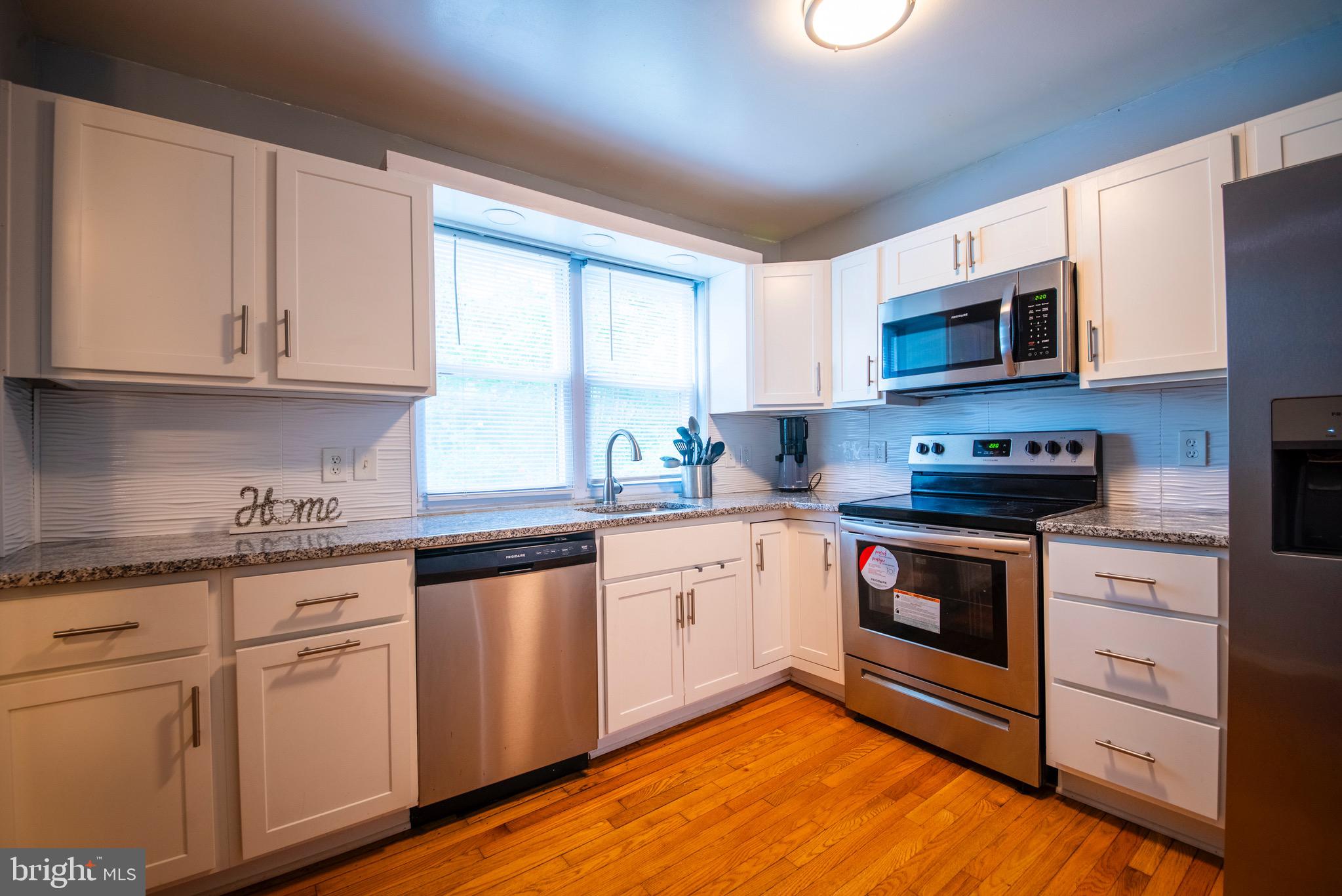 9355 Pan Ridge Road, Unit 9355 Parkville, MD 21234 - Photo 6 of 32 a kitchen with granite countertop white cabinets and white appliances