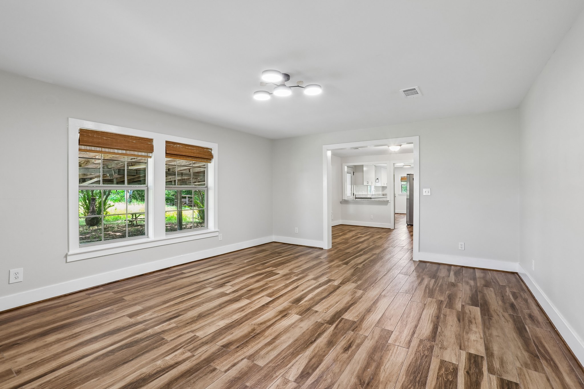 2089 Farm To Market Road 1704 Elgin, TX 78621 - Photo 6 of 31 A well-lit living area features warm wood-look flooring and an open flow to the kitchen beyond.