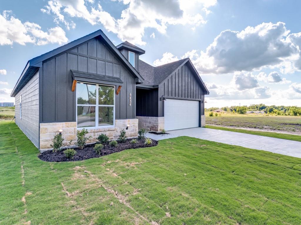 Modern farmhouse featuring board and batten siding, an attached garage, concrete driveway, a front yard, and roof with shingles