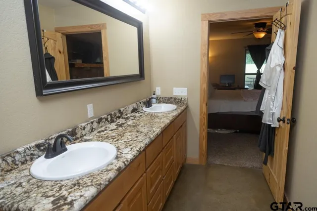 a en suite bathroom with a granite countertop sink and a mirror