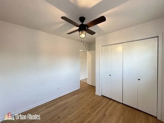 an empty room with wooden floor and ceiling fan