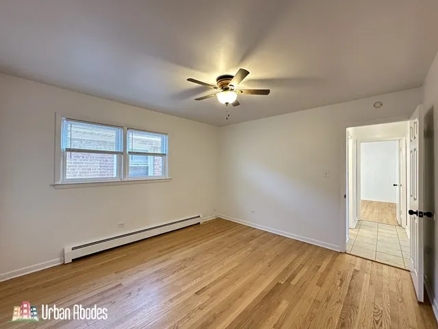 a view of empty room with wooden floor and fan