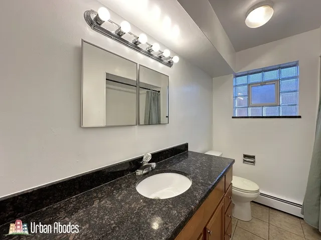 a bathroom with a granite countertop sink vanity mirror and toilet