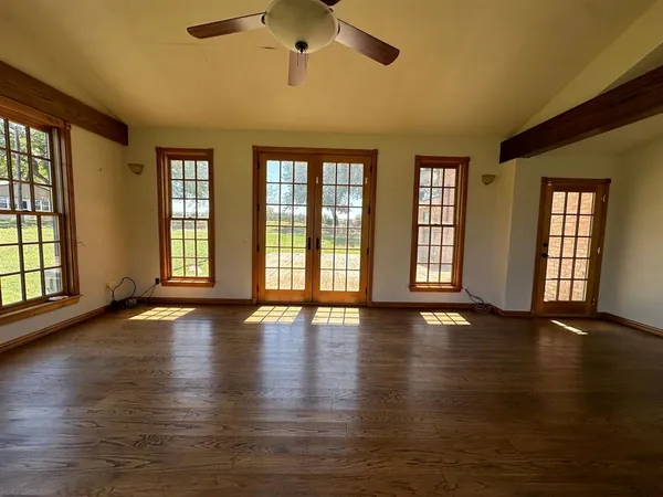 a view of an empty room with wooden floor and a window