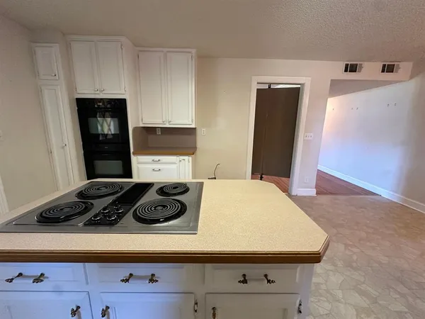 a room with kitchen island a stove a refrigerator a sink and cabinets