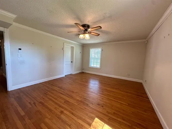 a view of an empty room with window and wooden floor