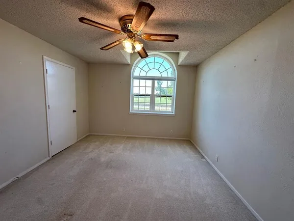 an empty room with windows and fan