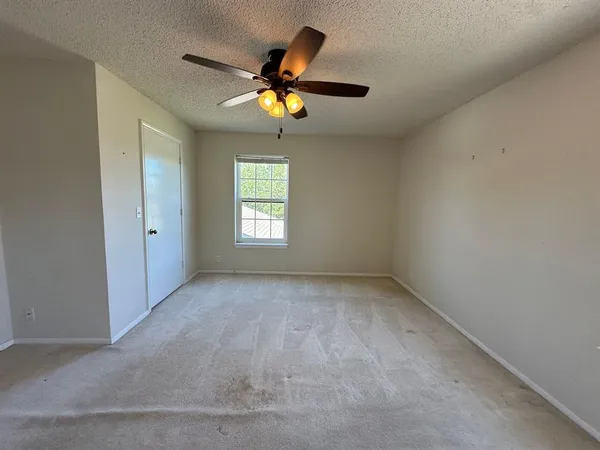 an empty room with windows and chandelier fan