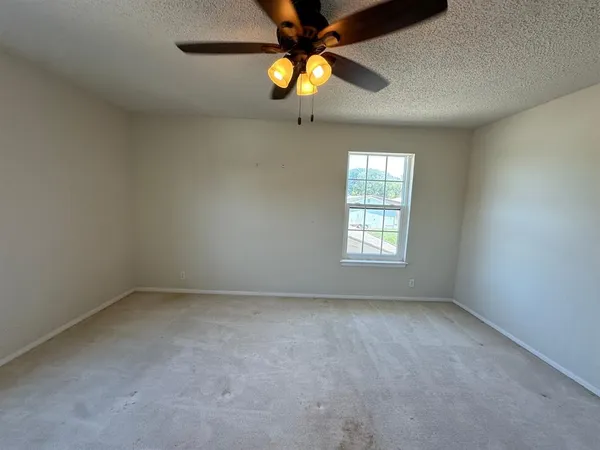 an empty room with windows and a chandelier fan
