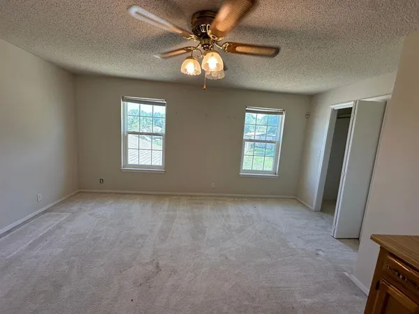 a view of an empty room with window and chandelier fan