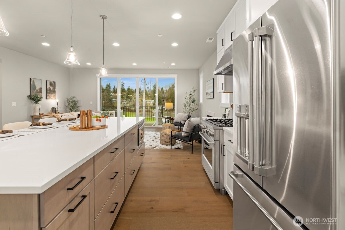 7879 South 132nd Street Seattle, WA 98178 - Photo 11 of 37 a kitchen with kitchen island a counter top space a sink a refrigerator and a view of living room
