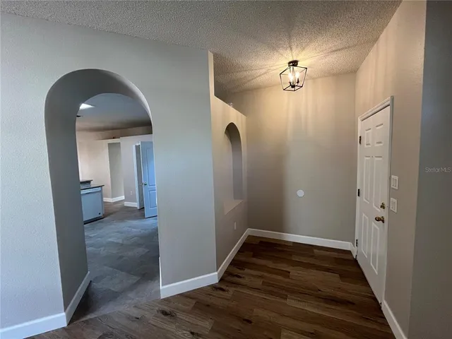 a view of a hallway with wooden floor and a chandelier