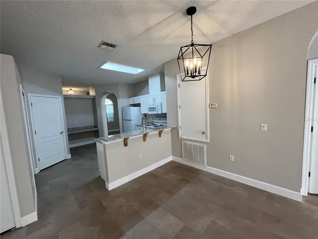 a view of a room with chandelier fan and kitchen view