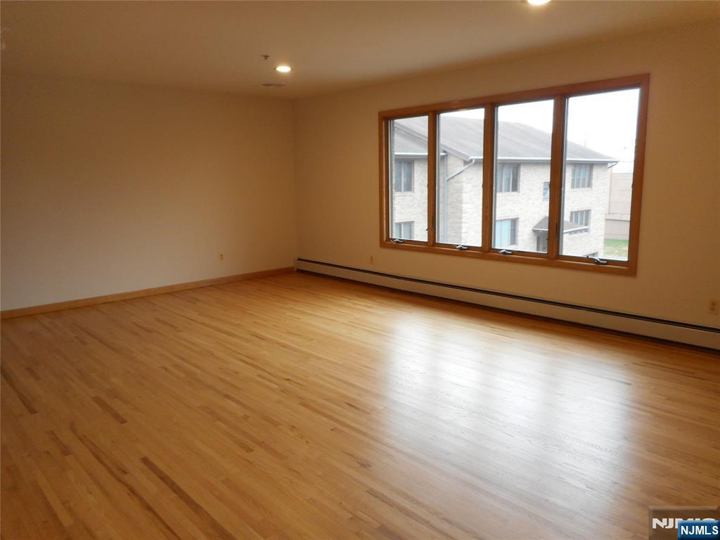 137 River Road, Unit 137 Clifton, NJ 07014 - Photo 4 of 21 an empty room with wooden floor and windows