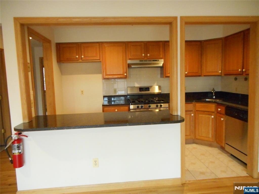 137 River Road, Unit 137 Clifton, NJ 07014 - Photo 6 of 21 a kitchen with stainless steel appliances a refrigerator a sink and wooden cabinets