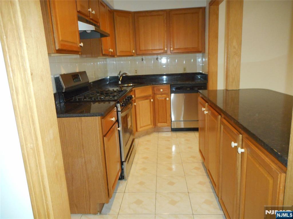 137 River Road, Unit 137 Clifton, NJ 07014 - Photo 8 of 21 a kitchen with a sink a stove top oven and cabinets