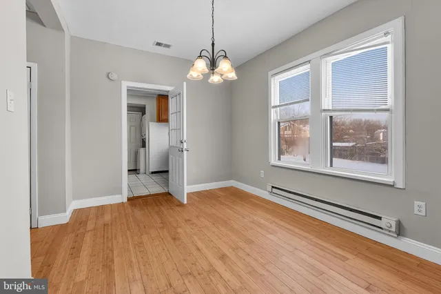 a view of an empty room with a window and wooden floor