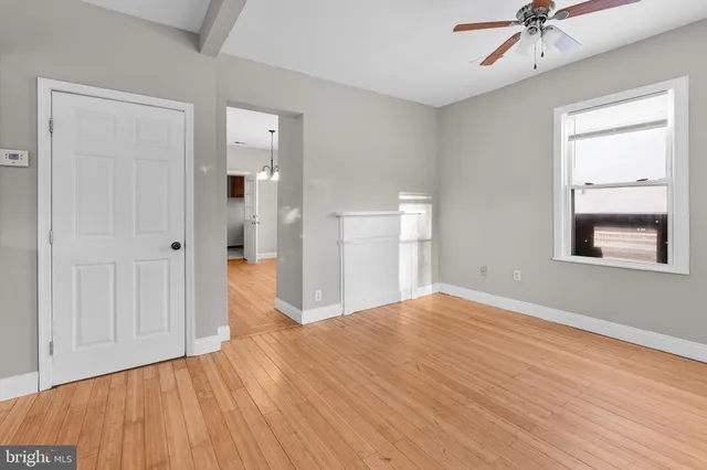 a view of empty room with wooden floor and fan