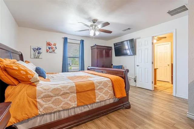 a bed sitting in a bedroom and view of kitchen with wooden floor