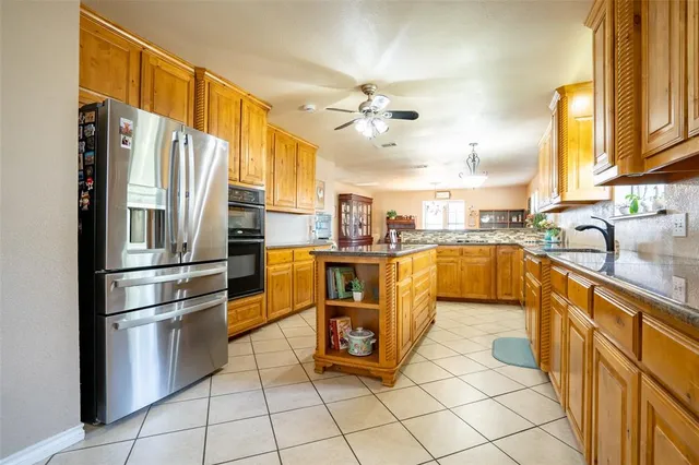 a kitchen with stainless steel appliances granite countertop a refrigerator a sink a stove and white cabinets