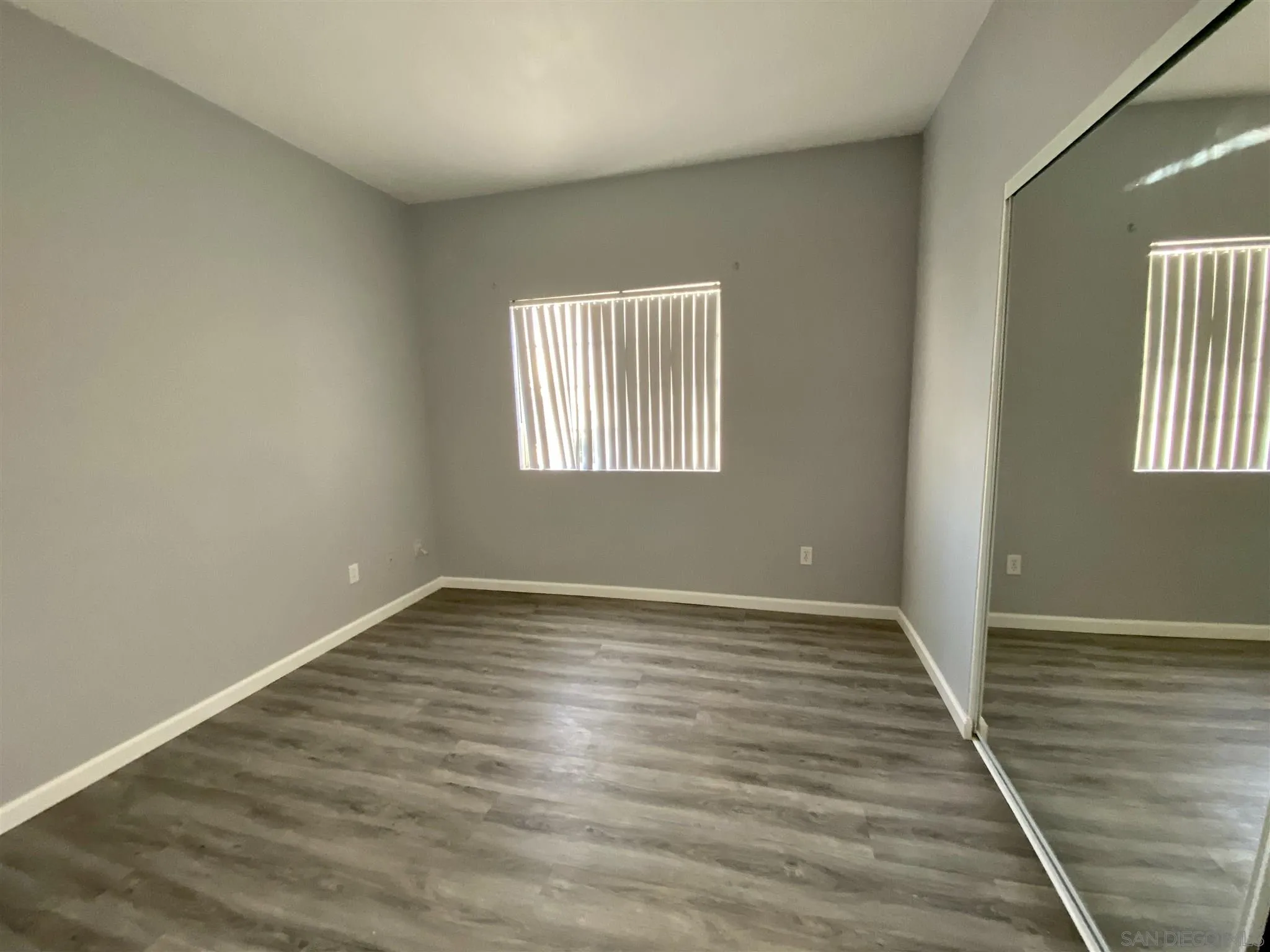 17161 Alva Road, Unit 213 San Diego, CA 92127 - Photo 10 of 48 a view of an empty room with wooden floor and a window