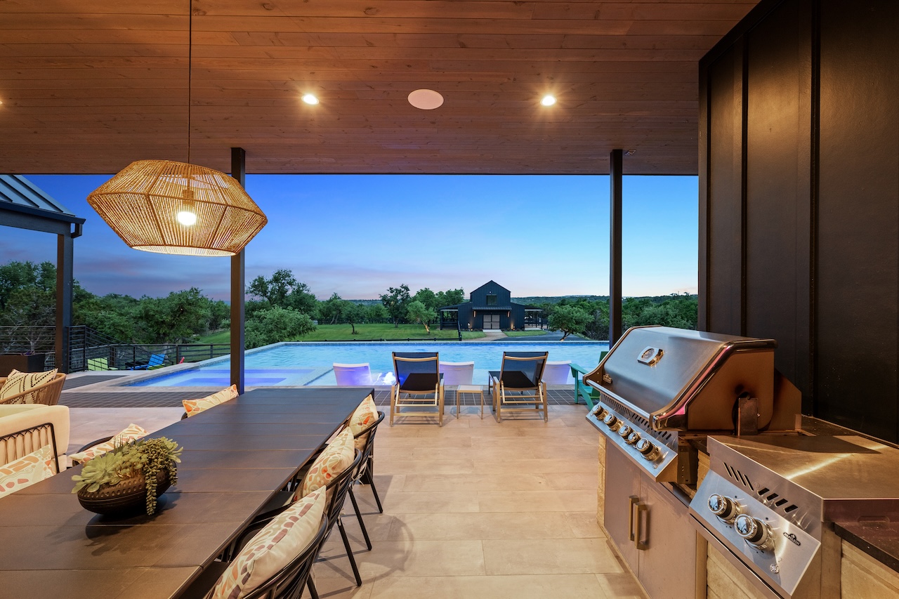 475 Happy Trail Dripping Springs, TX 78620 - Photo 23 of 40 Outdoor living area with room for a large dining table, a built-in outdoor grill, a swimming pool, and views of the surrounding landscape
