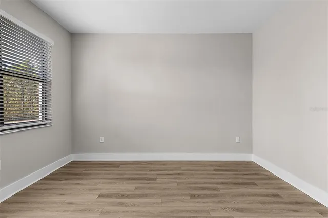 a view of an empty room with wooden floor and a window