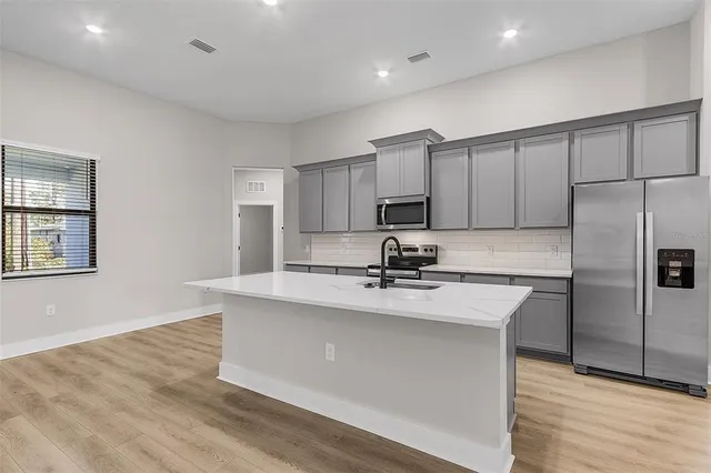 a kitchen with kitchen island a sink stainless steel appliances and cabinets
