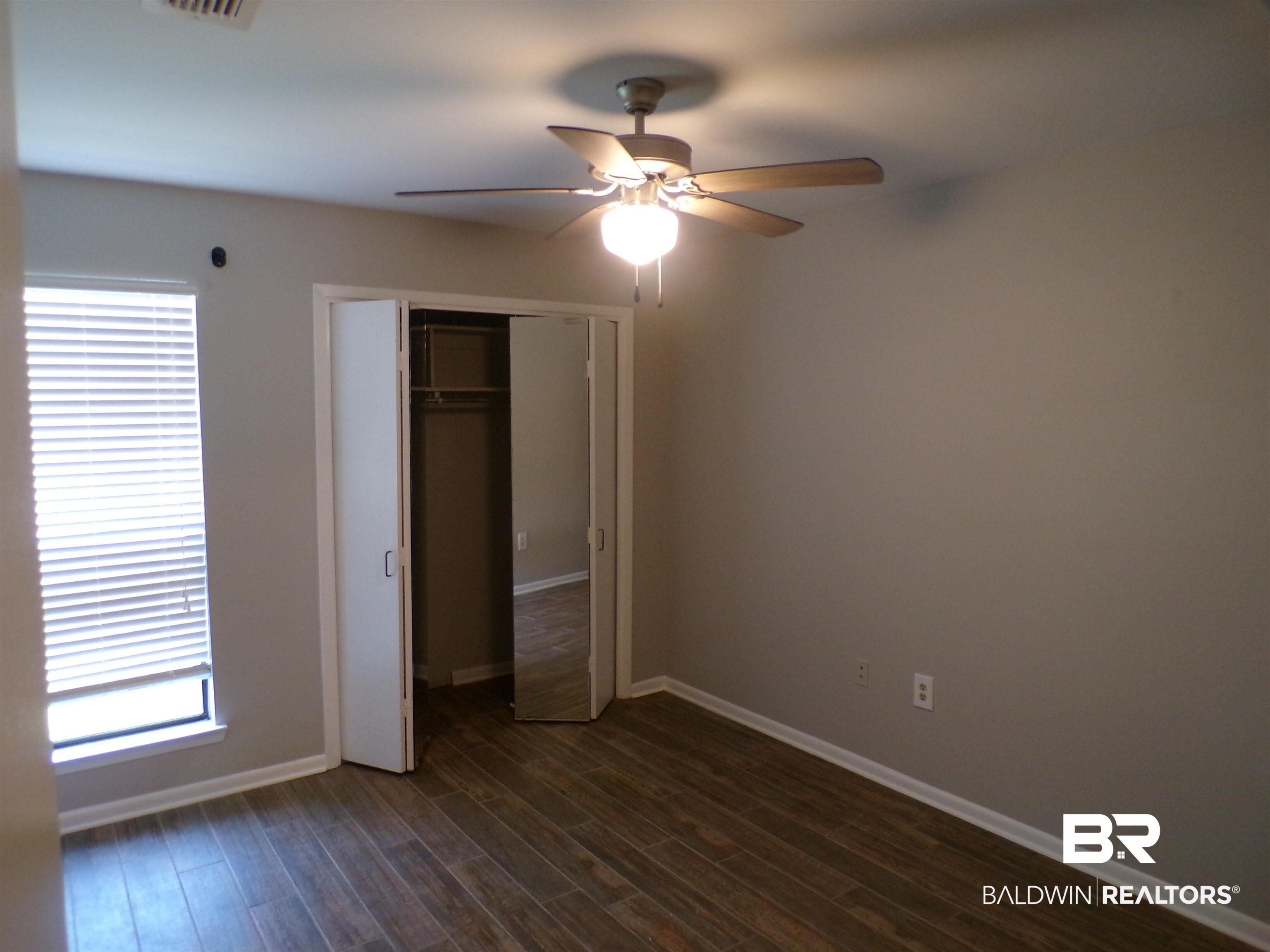 1152 North Alston Street, Unit 1152 Foley, AL 36535 - Photo 15 of 16 Room featuring wood-finish flooring, a ceiling fan with integrated lighting, and a window with blinds