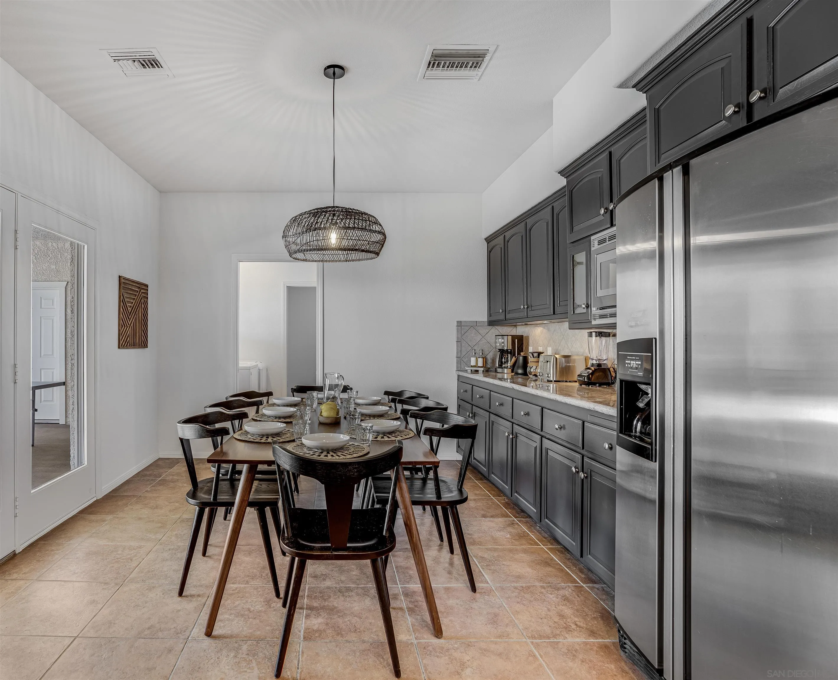 9255 Del Monte Avenue Yucca Valley, CA 92284 - Photo 9 of 46 a kitchen with stainless steel appliances kitchen island granite countertop a dining table chairs and white cabinets