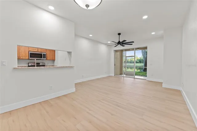 a view of a livingroom with a flat screen tv wooden floor and a ceiling fan