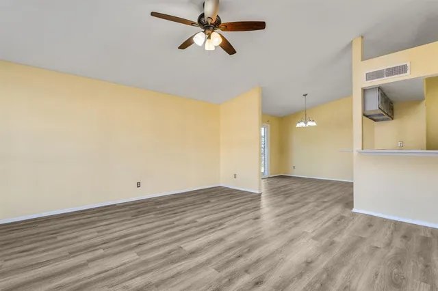 a view of a room with wooden floor and a ceiling fan