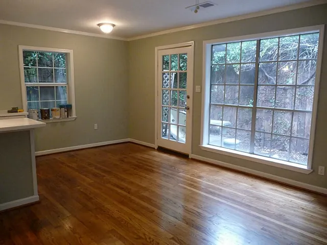 an empty room with wooden floor and windows