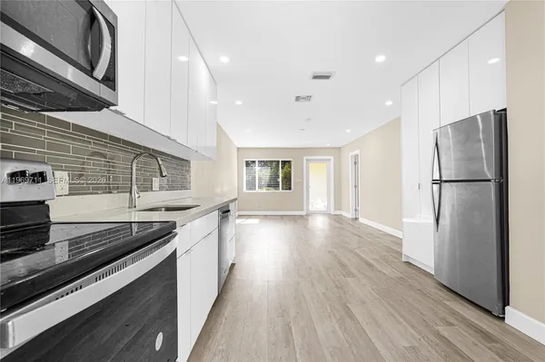 a kitchen with stainless steel appliances granite countertop a refrigerator a stove and a wooden floors