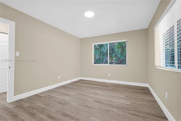 an empty room with wooden floor and windows