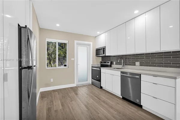a kitchen with a refrigerator and white cabinets