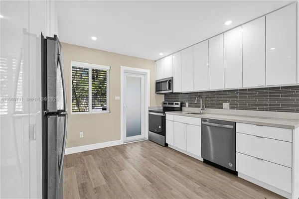 a kitchen with a refrigerator and white cabinets