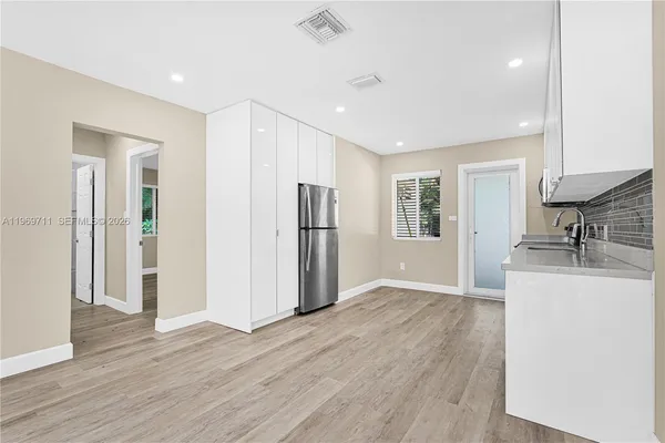 a view of a kitchen with a sink refrigerator and wooden floor