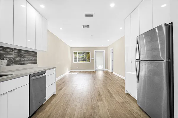 a kitchen with a refrigerator a sink and wooden floor