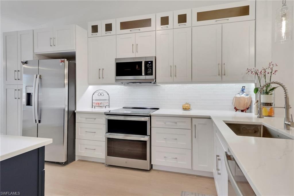 2386 Magnolia Avenue, Unit 7816 Naples, FL 34112 - Photo 4 of 28 a kitchen with white cabinets and stainless steel appliances