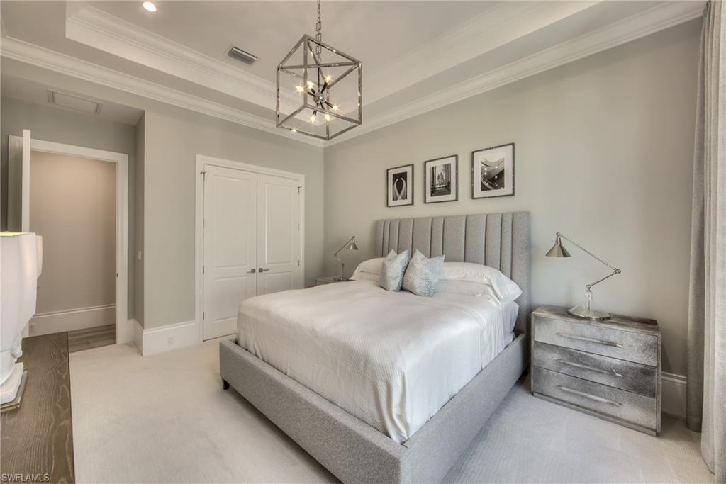 13981 Williston Way Naples, FL 34119 - Photo 11 of 13 a spacious bedroom with a bed and a chandelier