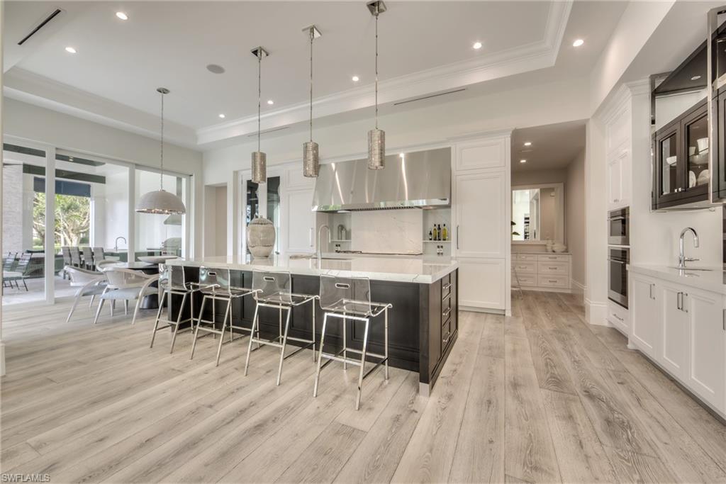 13981 Williston Way Naples, FL 34119 - Photo 3 of 13 a large kitchen with kitchen island a island a stove a table and chair in it