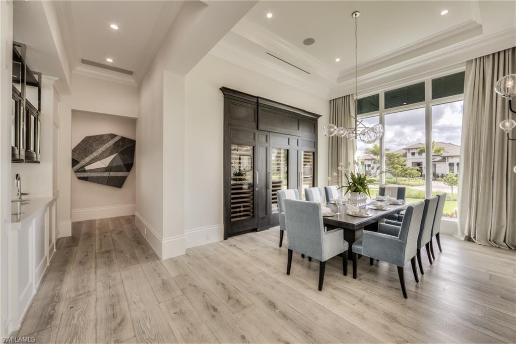 13981 Williston Way Naples, FL 34119 - Photo 6 of 13 a dining room with wooden floor a chandelier a wooden table and chairs